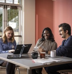 Three Marcus Institute team members converse while sitting at a table in the break area.