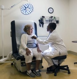 A doctor at Hebrew SeniorLife in Boston, MA uses a stethoscope to listen to the heart of an older woman.