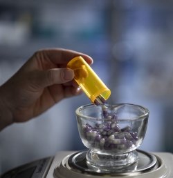 A pharmacist at Hebrew Rehabilitation Center in Boston, MA measures out pills.