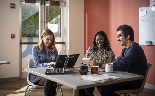 Three Marcus Institute team members converse while sitting at a table in the break area.